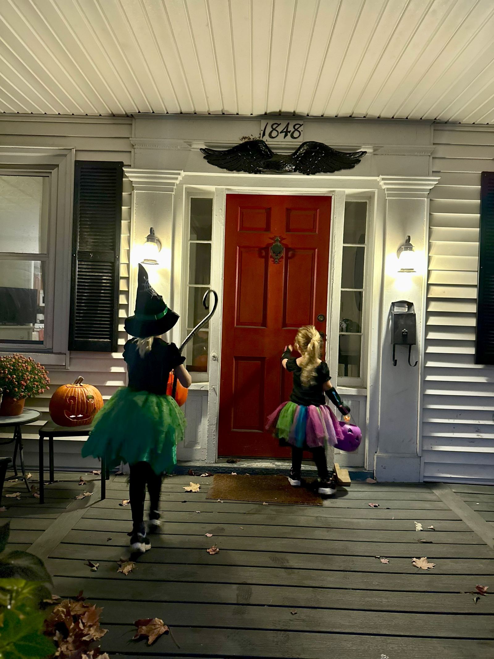 Two girls trick-or-treating at a historic Salem house decorated for Halloween